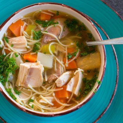 fresh cooked chicken noodle soup in a large bowl from above on dark table background. Ready to eat